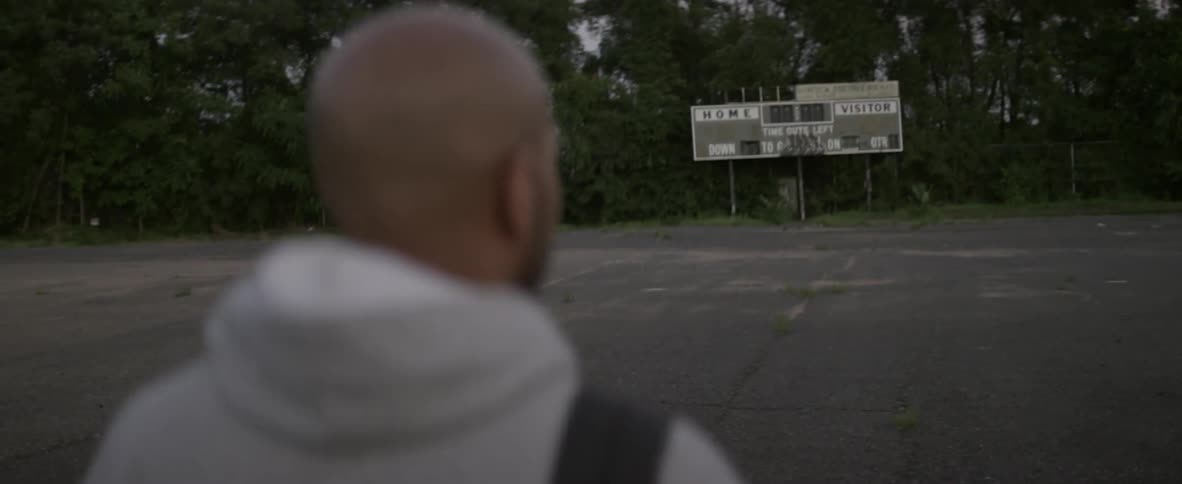 A man walks down the field towards a billboard