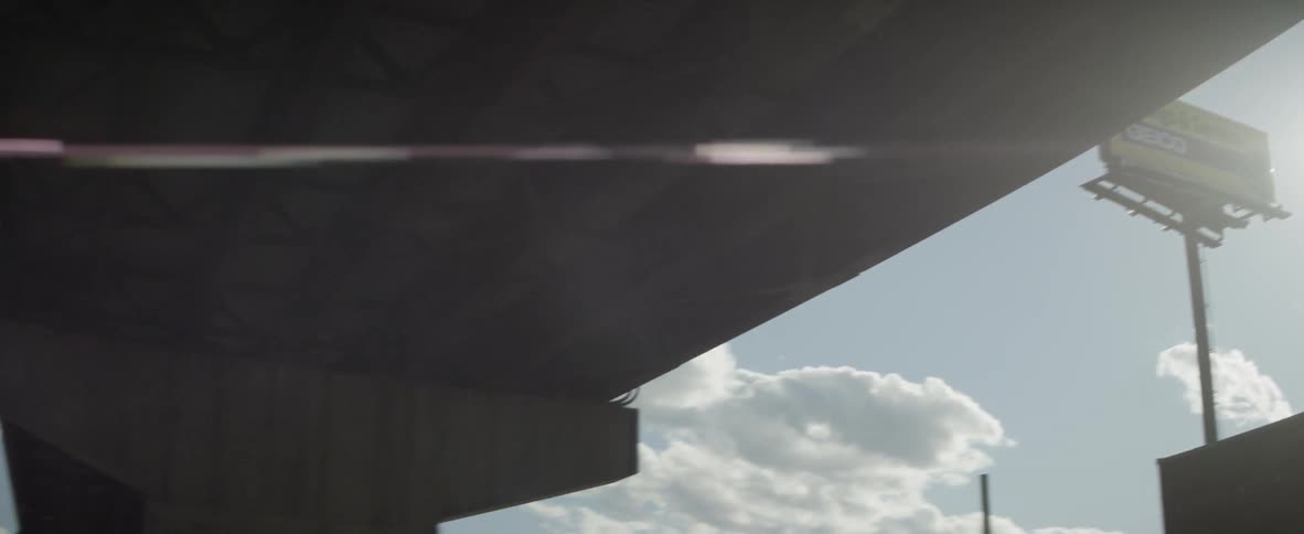 The sun shines under a highway