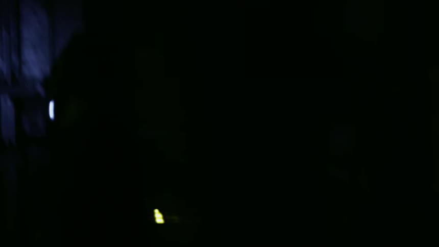 People with flashlights move past a brick building