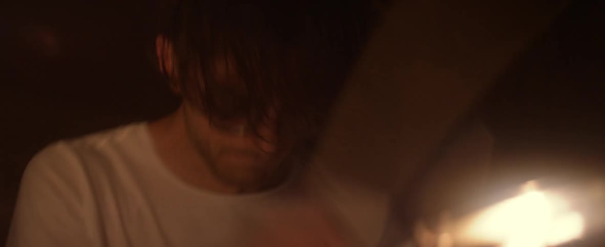 Man plays drums in a dimly lit room