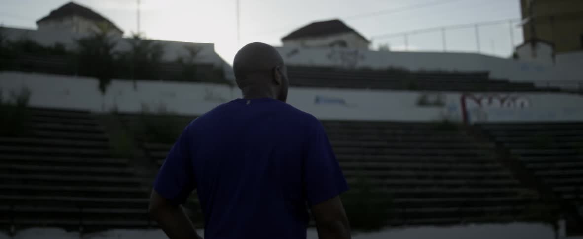 A man walks in an abandoned stadium on a sunny day