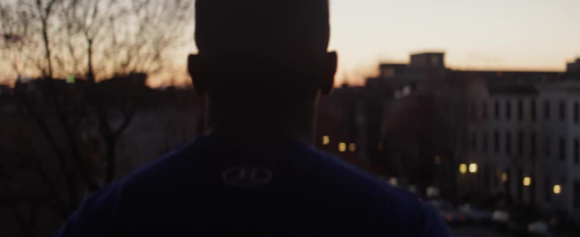 A man bounces while looking at city buildings at sunset