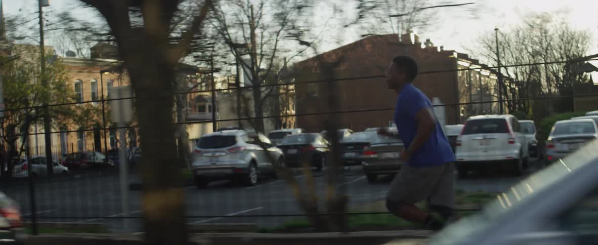 A man is running down the sidewalk on a sunny day