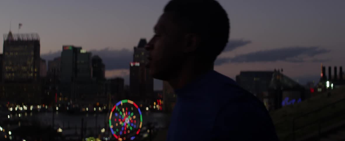 A man is stretching with a ferris wheel in the background