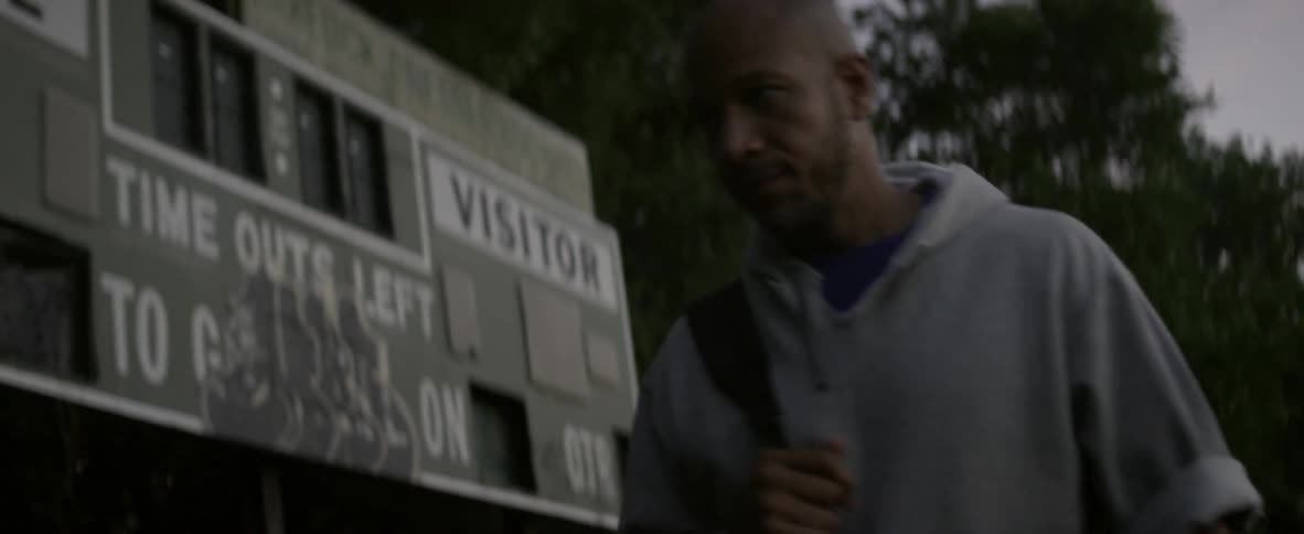 A man in a hoodie walks past a sign