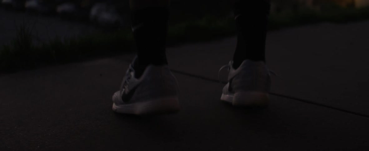 Person bouncing up and down on their tiptoes as seen from their shins down in a dimly lit area