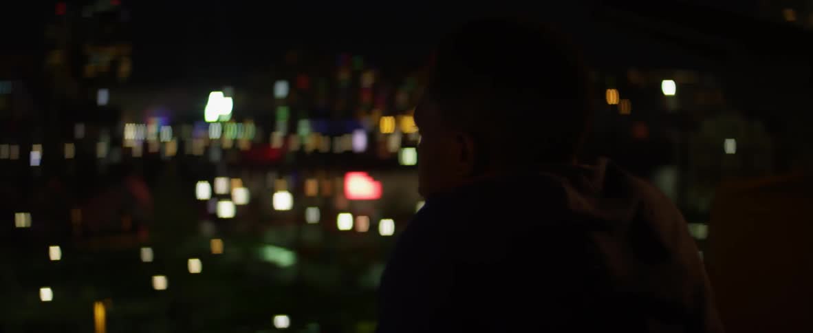 A man looks at city lights at night