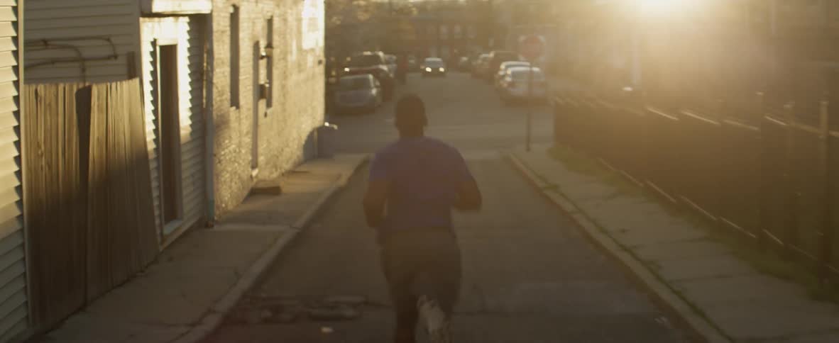 A man is jogging down the street at sunrise