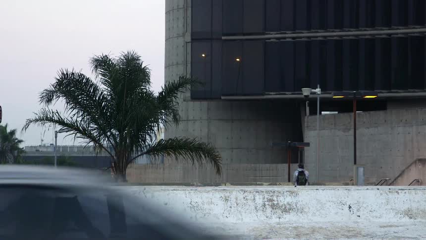 A person stands near the street as cars move past
