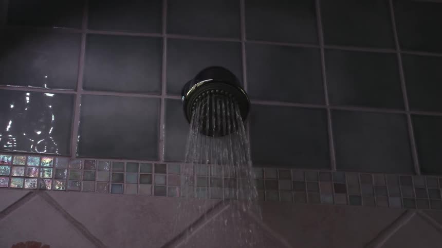 A shower head turns on pouring water down