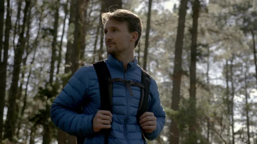 A man is standing outside looking out over the woods