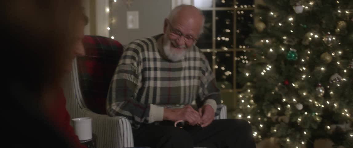Group of adults sitting and laughing around a christmas tree