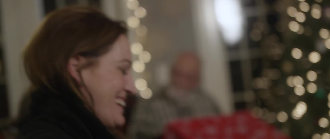 A close up shot of two people hugging next to a christmas tree