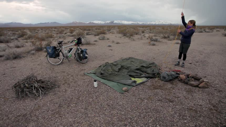 A woman is setting up a tent on the field