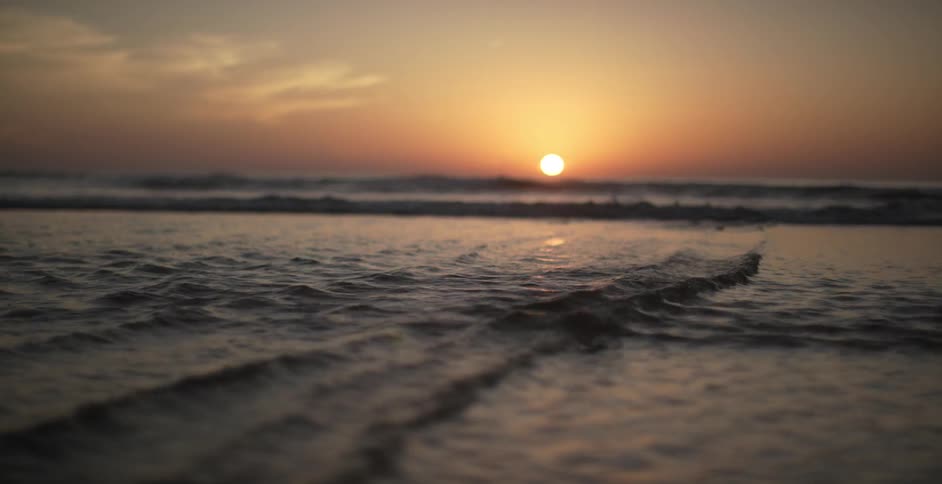 The sun sets over rippling ocean waves