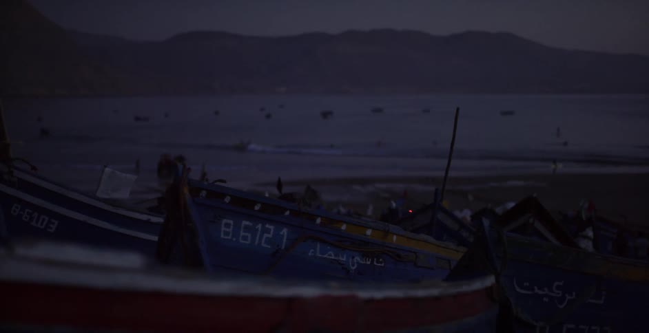 A red light blinks amid watercraft sitting on a beach