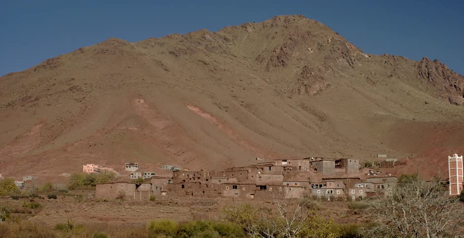 Buildings sit in front of a mountain on a clear day