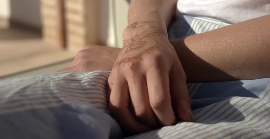 A person is sitting with their hands crossed together