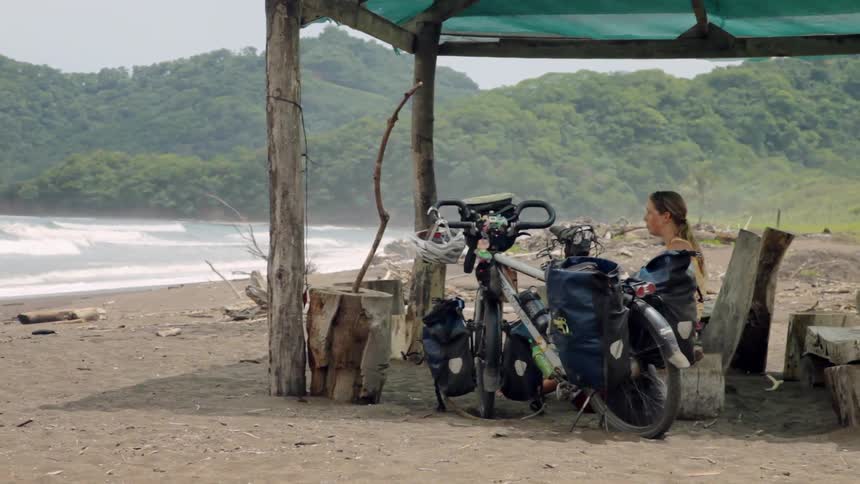 A woman sits under an awning on the beach