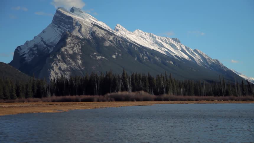 A lake ripples in front of a snowy mountain