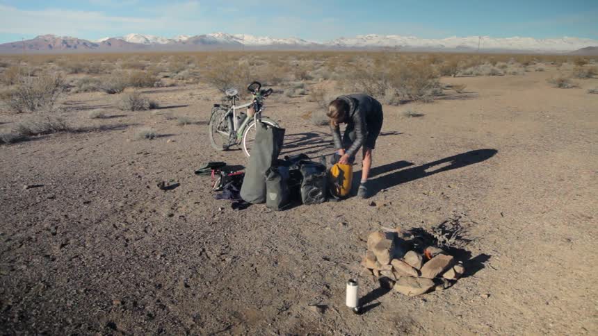 A woman is packing her bags by a camp