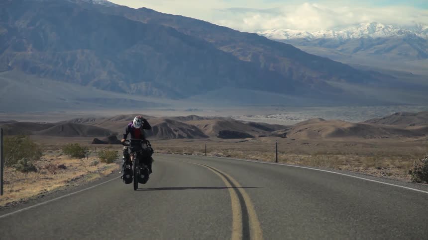 A man is riding his bicycle down a long road