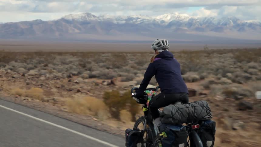 A person is riding a motorcycle down the road through the desert