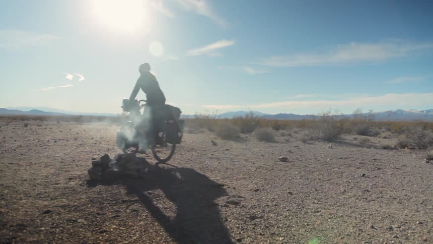 Person riding a bike away from a smoldering campfire