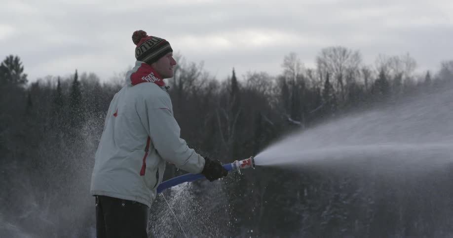 Man spraying water from a hose on a cloudy day