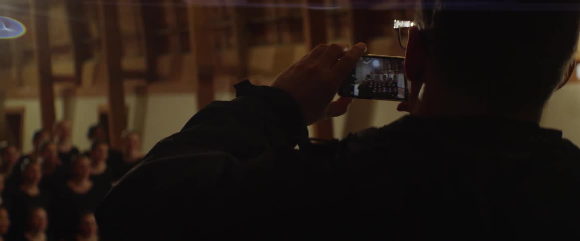 A man takes pictures of a group of women in dark dresses