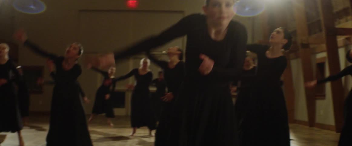 Women wearing black dresses dance in a large room