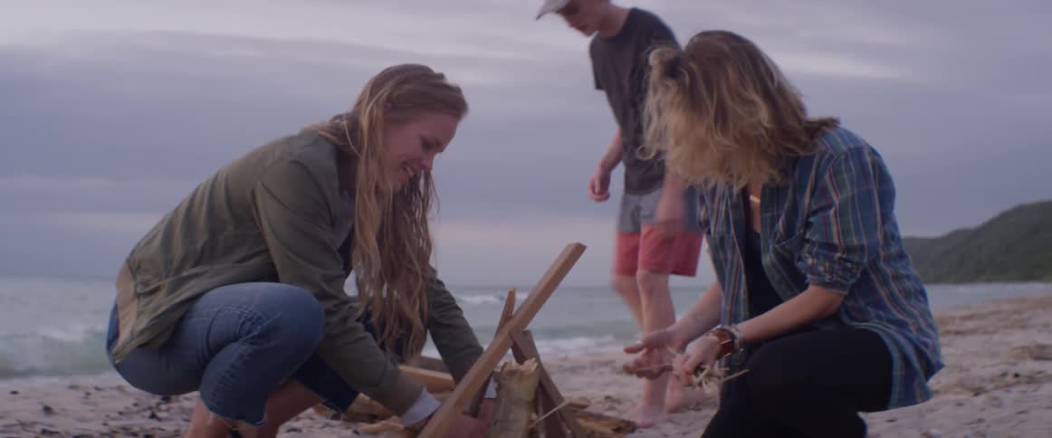 Three people gathering wood for a beach fire