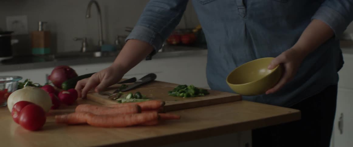 A woman pulls a bowl from a cabinet