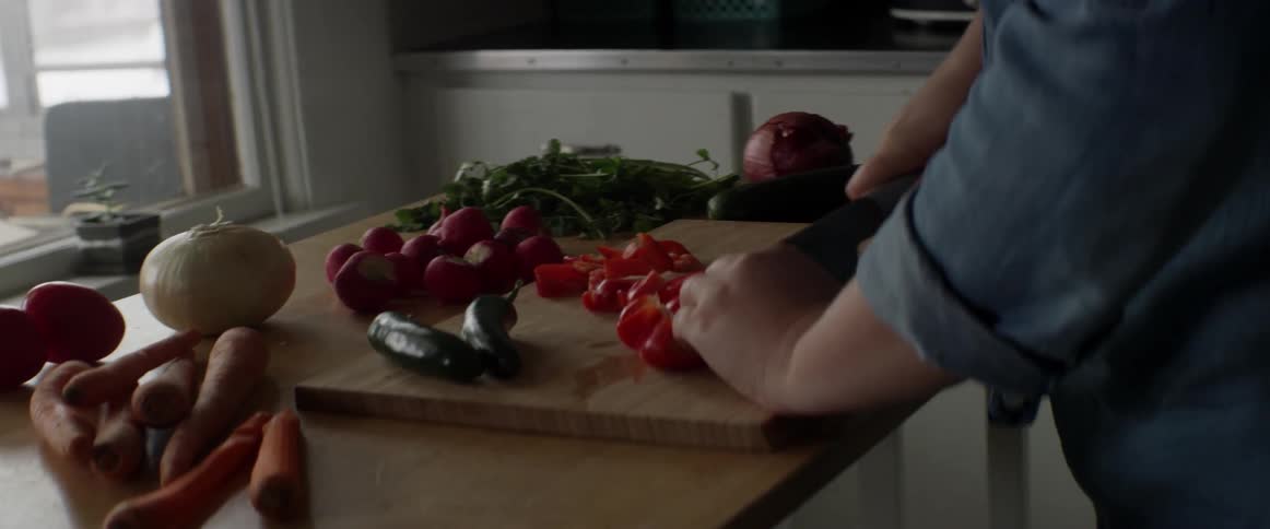 A woman is cutting peppers with a knife
