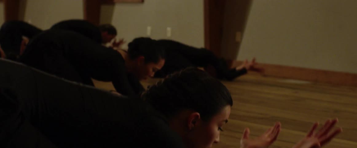 Women raise their arms all wearing black and dance
