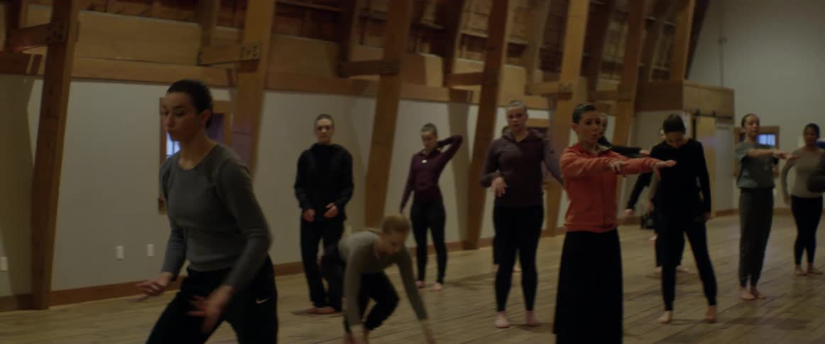 The women practice dancing together in the hall