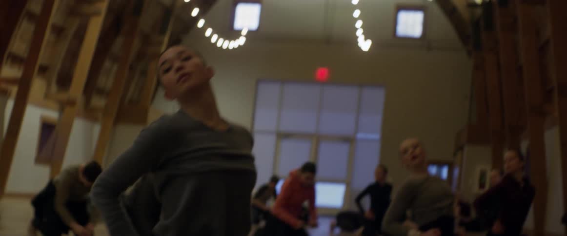 Women do stretches on a wooden floor in a large room