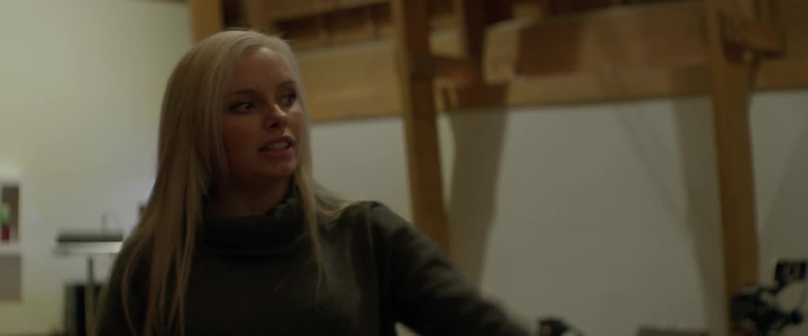 A blonde woman talks and gestures someone over