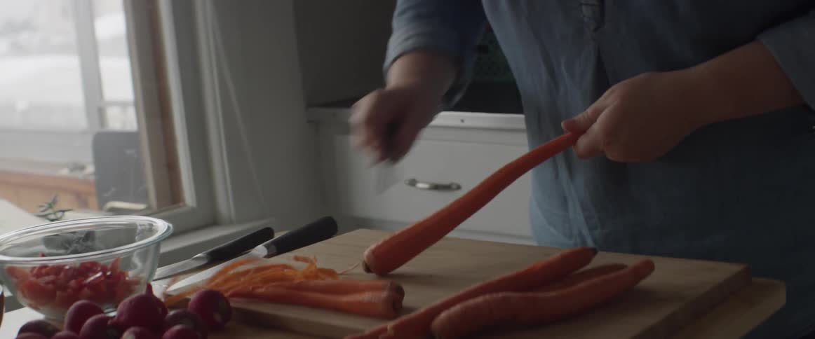 Woman peels carrots on a cutting board