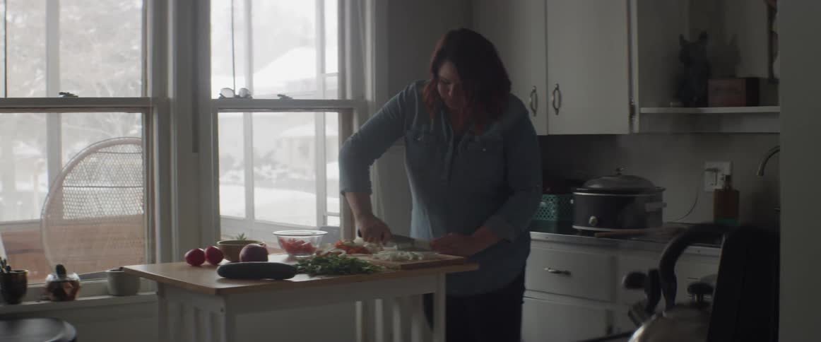 A woman is cutting vegetables on a board