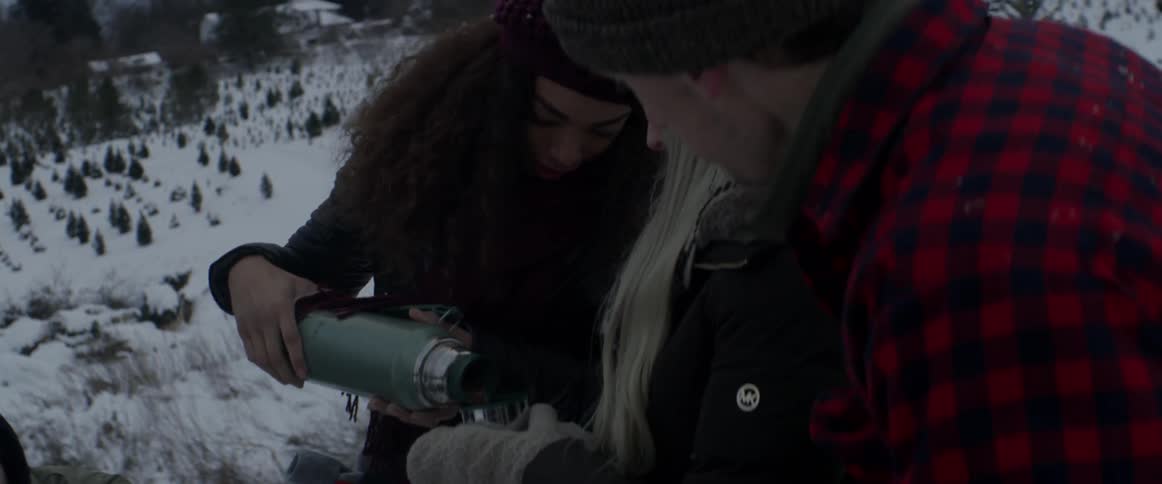People drink from a thermos outside on a snowy day