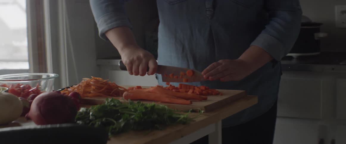 A woman is chopping up carrots