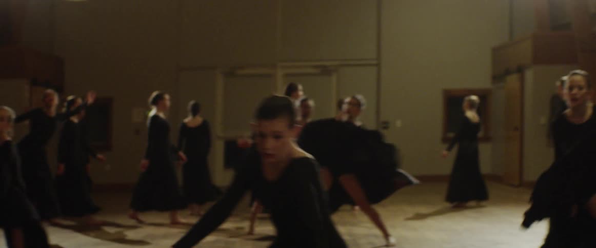 Women twirl their black dresses as they dance together