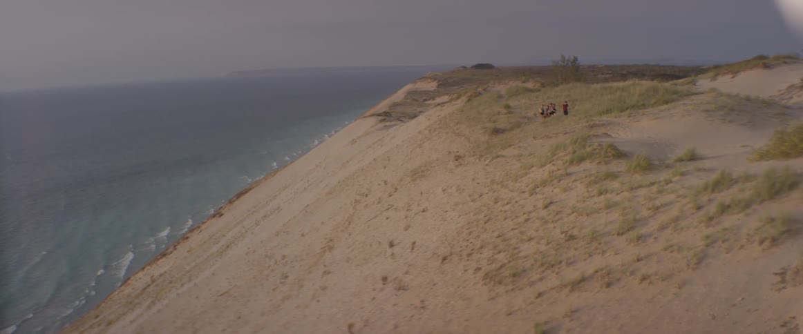 People walking high on a hill above a shoreline