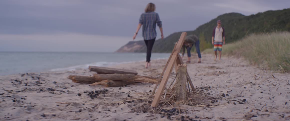 People gather wood for a bonfire on a beach