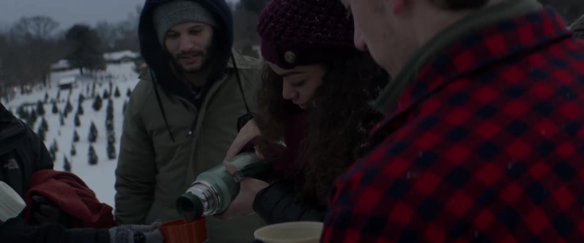A woman pours hot cocoa into a small red cup