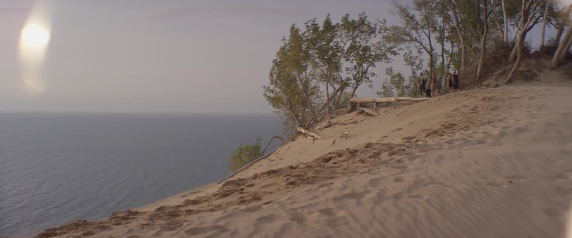 People hike on the hill above the beach