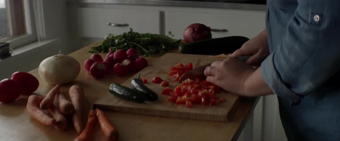 Person slicing vegetables on a cutting board in a kitchen