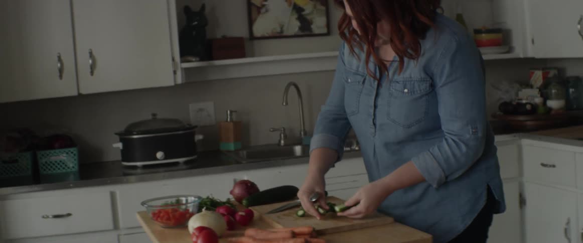 A woman chops vegetables in a kitchen