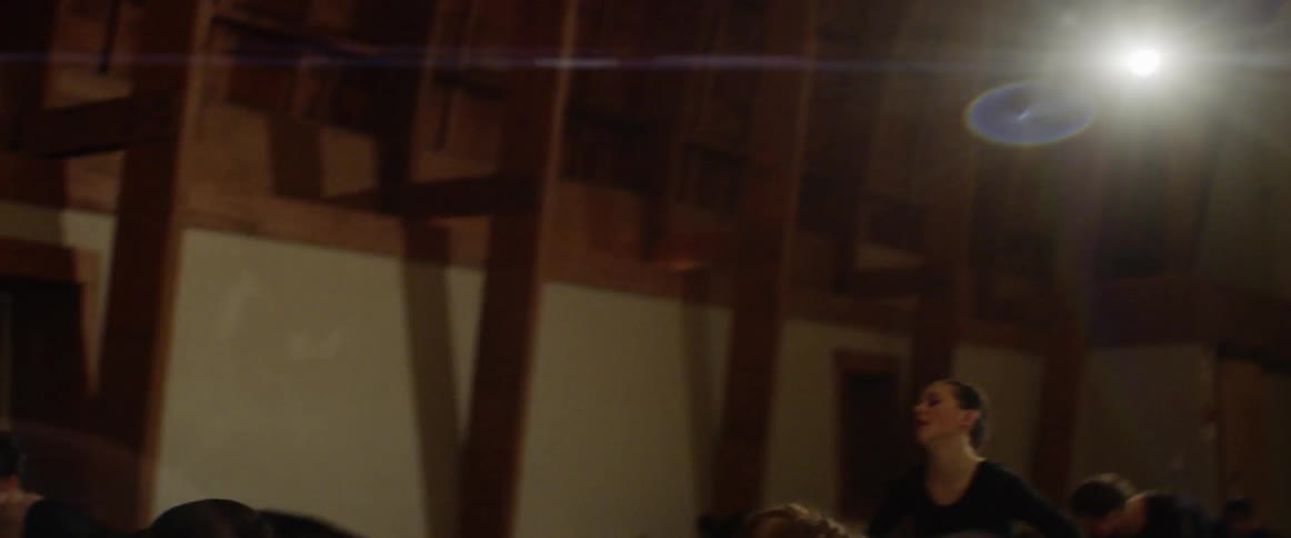 A group of women dance in a brightly lit room